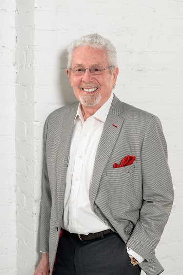 Terry Slattery in a gray suit coat on a white brick background