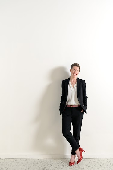 Jennica Dixon in a black suit and red shoes on a white background